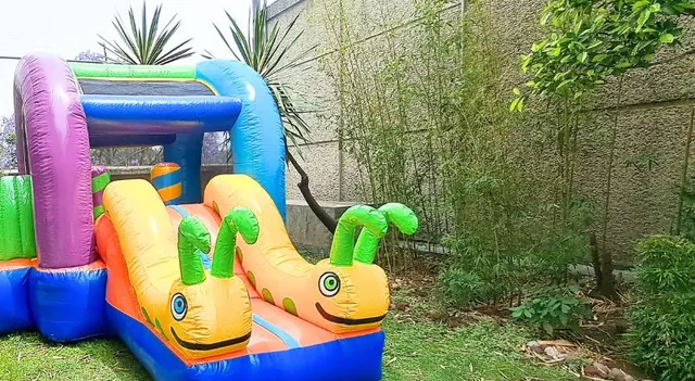 Inflable de colores con gusanitos sonrientes en un jardín