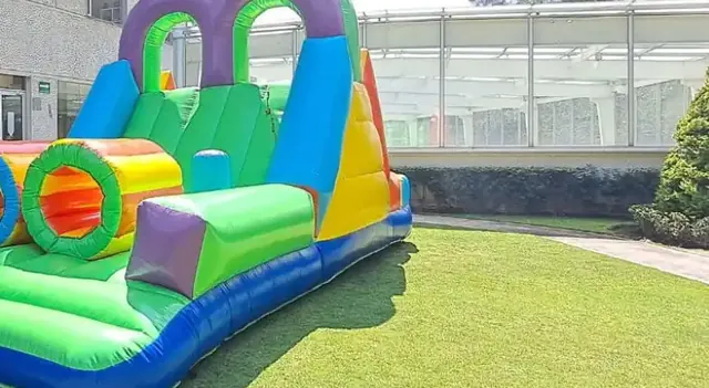 Tobogán inflable con túneles de colores sobre el pasto