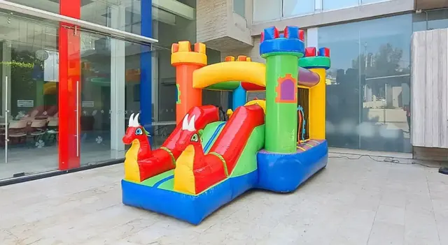 Castillo inflable DRAGONES ROJOS instalado en una explanada frente a un edificio