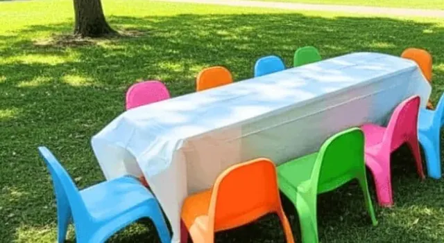 Mesa para niños con sillas azules, naranjas, verdes y rosas sobre el pasto