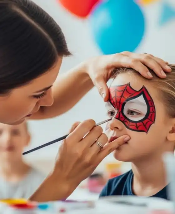 Pintacaritas profesional pintando una máscara de Spider-Man en la cara de un niño
