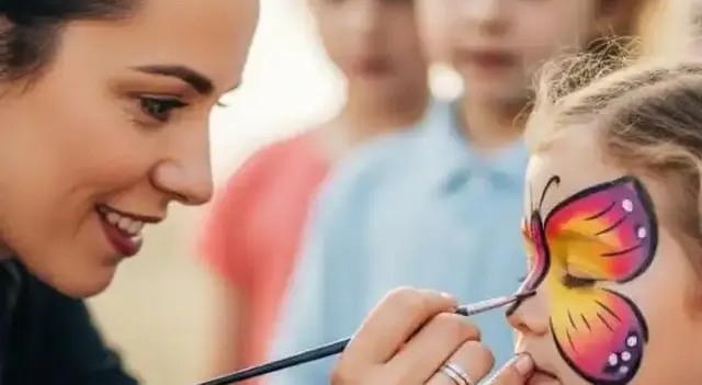 Pintacaritas pintando un diseño de colores en la cara de un niño